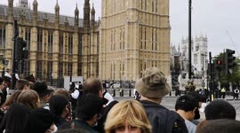 People outside the secuitey barriers hear the start of the Queen's funeral procession