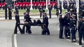 Police officer who felt unwell is carried on stretcher by Navy soldiers during Queen's procession