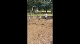 Boy tries to jump over swing but gets his foot caught in it and falls down