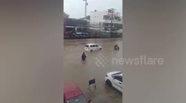 Riders and pedestrians wade through flooded road in the Philippines