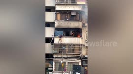 Men climb building carrying hose to extinguish second-floor balcony in China