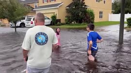 Family walks through flood during Hurricane Ian