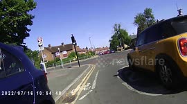 Cycling down the road when a yellow mini overtakes and does a left turn.