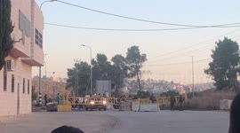 Israeli settlers gather while Israeli forces prevent Palestinians cross a military checkpoint