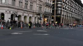 The last runners if the London Marathon run the last mile as the clean up crew behind them