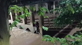 Volunteers dive into swollen river to save Chinese tourist stranded on bridge during high floods in Thailand
