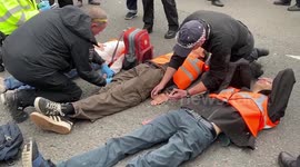 Police officers arrest Just Stop Oil climate activists who glued themselves to the roads in Parliament Square