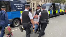 Police officers arrest Just Stop Oil climate activists who glued themselves to the roads in Parliament Square