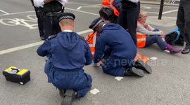 Police officers arrest Just Stop Oil climate activists who glued themselves to the roads in Parliament Square