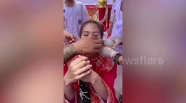 Devotee has her cheeks pierced with metal skewers during Vegetarian Festival in Thailand