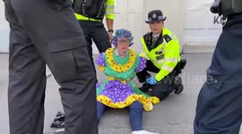 Police officers remove climate protest in fancy dress from road in central London