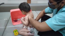 Cute toddler having massage by masseur at baby spa Malaysia
