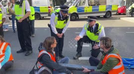 Just Stop Oil activists block the junction of Marylebone Road and Baker Street in London.  The police are trying to remove the protesters.