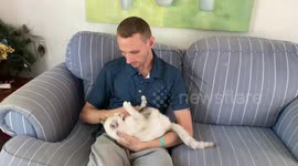 My son is holding his cat, who freaks out whenever the door is opened.