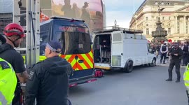 Police officers climb onto a police van to remove Just Stop Oil activist who glued himself to the roof