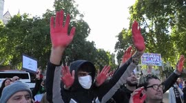 Iranian men chant for Mahsa Amini with red palms symbolising blood during protest at Parliament Square