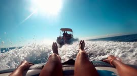 Young woman water skiing over inflatable donut pulled by motorboat.