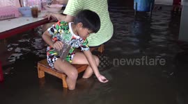 Diners eat with fish snapping at their heels in flooded restaurant in Thailand