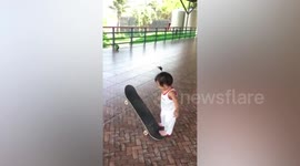 Talented toddler effortlessly rides skateboard during practice with mother