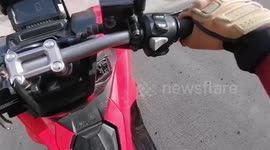 Jaywalking pedestrian shrugs off near-miss with motorcycle as it brakes in front of her