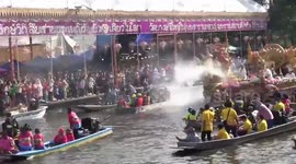 Buddhist devotees throw lotus flowers on passing boat with statues for festival in Thailand