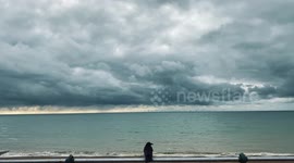 A crow watches the Rampion WindFarm in Brighton on a stormy sky October day and flies off
