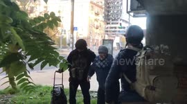 Military officers help old woman with walking stick shelter from explosions in Kyiv