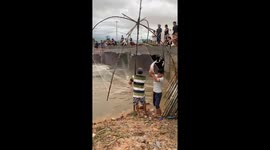 Dozens of people plunge into the fast-flowing flood water to catch fish