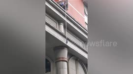 Kitten falling from building caught by residents holding bed sheet below