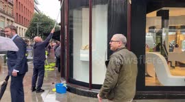 Workers clean windows after Just Stop Oil protesters sprayed orange paint on a Harrods store in Knightsbridge.