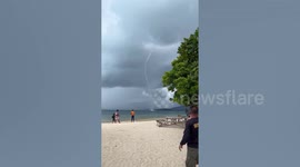 Enormous waterspout surfs along water near beach in the Philippines
