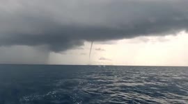 Thin waterspout tornado forms next to rain curtain at sea in the Philippines