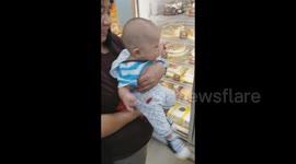 Baby excited to buy his first cake roll in the mall