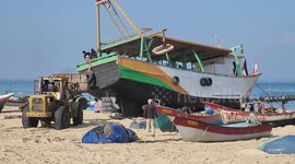 Palestinians gather during the launch of the largest fishing boat