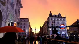 Torrential rain passes revealing vivid orange sunset over Piccadilly Circus