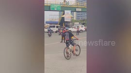 Amazing cyclist carries bucket and three containers on head while riding