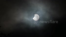 Partial solar eclipse viewed above the cloudy skies of Birmingham, England during rare event visible from Earth