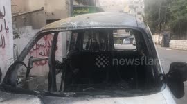 Palestinians look at a damaged car following an overnight Israeli raid in Nablus, in the West Bank