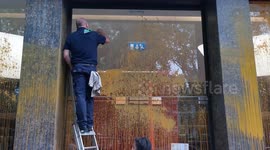 Cleaners remove orange paint from the exterior of a luxury car showroom after it was sprayed by Just Stop Oil