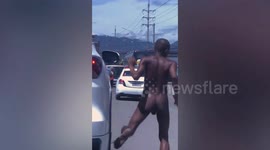 Bizarre moment naked man hitches free ride on SUV