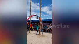 Tourist struggles to climb a greasy pole at a festival in Thailand