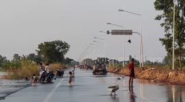 Children play on flooded road following heavy rain in Thailand