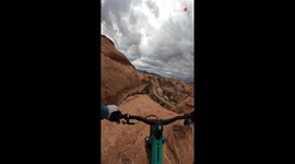 Daring cyclist cruises down 10-story-tall sandstone rock
