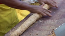 Street food vendors use large wooden hammers to pound sweet peanut street food snack
