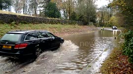 Cars drive through flood water in Kendal Cumbria