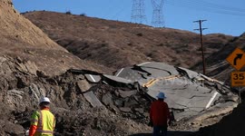 Workers inspect landslide buckled road in California V19282