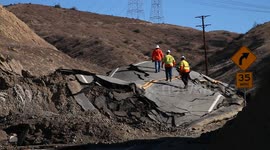 Workers inspect landslide buckled road in California V19283