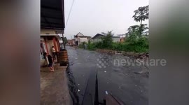 Trash-filled flood gushes through village street after rain in Indonesia
