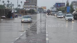 Palestinians walk in a street flooded by rain water, in Gaza city