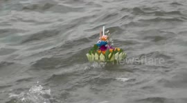 Buddhist devotees float candle-lit flower baskets on water to celebrate annual water goddess festival